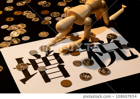 A doll with drooping heads suffering from the tax increase amid scattered coins 108687654