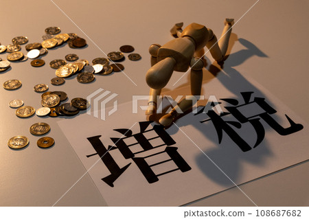 A doll with drooping heads suffering from the tax increase amid scattered coins 108687682