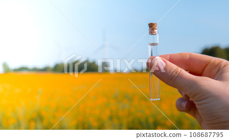 Hand holding test tube with liquid on background of canola flowers field blooming farm. Rapeseed oil over natural background. Farmer soil sample in tube chemical analysis ph test. Agrochemical Hand holding test tube with liquid on background of canola flowers field blooming farm. Rapeseed oil over natural background. Farmer soil sample in tube chemical analysis ph test. Agrochemical 108687795