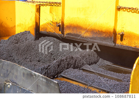 Asphalt pavement is laid on top of gravel base using pavement machine during construction highway 108687811