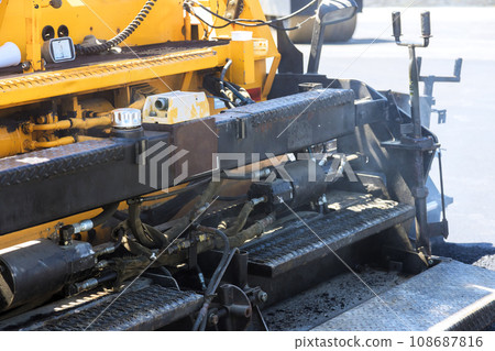 In course of road construction bitumen asphalt layer is laid on top gravel base by pavement machine 108687816