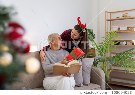 Family winter holiday and concept happy mother and daughter decorate christmas tree and give a gift at home Family winter holiday and concept happy mother and daughter decorate christmas tree and give a gift at home 108694038