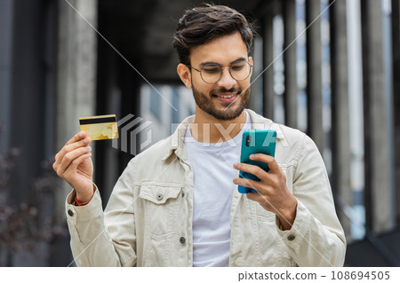 Indian man using credit bank card smartphone while transferring money, purchases online shopping 108694505