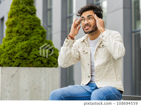 Displeased sick Indian man rubbing temples to cure headache problem, suffering from migraine, stress 108694559