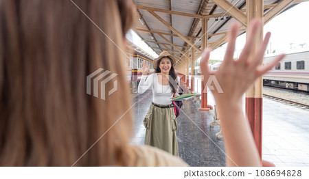 Asian female tourist waves greet to friend who are going on a trip at the train station 108694828