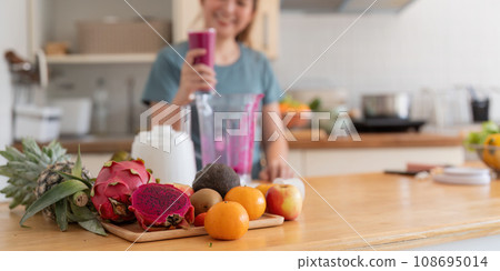 Beauty healthy asian woman making fruit smoothie with blender. woman drinking glass of fruit smoothie in kitchen. Diet concept. healthy drink 108695014