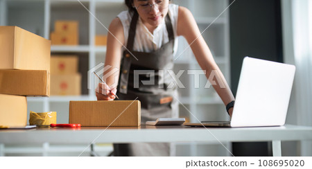Closeup woman Asian is writing a list of customer on paper before shipping to them, she runs an ecommerce business on websites and social media Closeup woman Asian is writing a list of customer on paper before shipping to them, she runs an ecommerce business on websites and social media 108695020