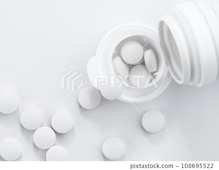 Top view of white pills out of white bottle with copy space. 108695522