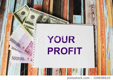 Notepad with the text YOUR PROFIT, dollars and euros lie on a colored striped background. Notepad with the text YOUR PROFIT, dollars and euros lie on a colored striped background. 108696620
