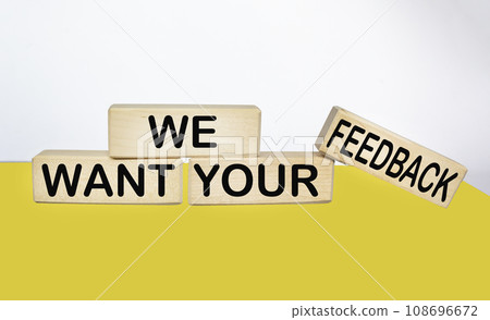 We need your feedback text on wooden block and yellow and white background 108696672