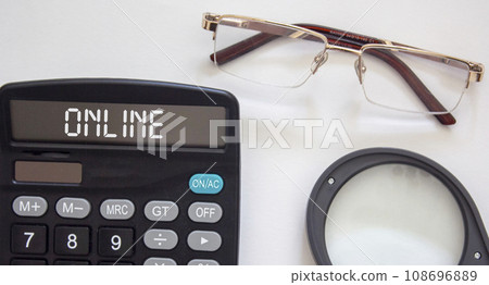Online text on a calculator, near glasses and a magnifier on a white background 108696889
