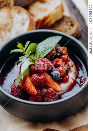 Tasty baked Camembert brie cheese with cranberry sauce and berries in restaurant. Gourmet appetizer 108698102