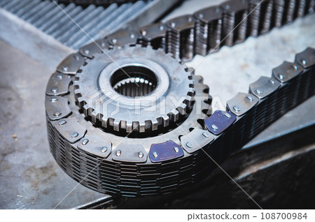Chain with gears of a disassembled transfer case. Gear synchronization and diagram, transmission detail in a makeshift workshop Chain with gears of a disassembled transfer case. Gear synchronization and diagram, transmission detail in a makeshift workshop 108700984