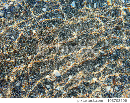 Pebble stones underwater, sea ripples background Pebble stones underwater, sea ripples background 108702306