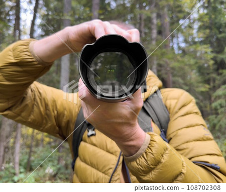 Photographer taking photo in nature, holding digital camera Photographer taking photo in nature, holding digital camera 108702308
