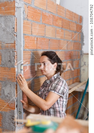 Woman measuring wall with level Woman measuring wall with level 108704792