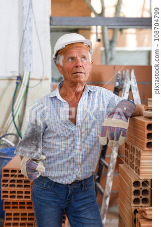 Thoughtful foreman near stack of bricks Thoughtful foreman near stack of bricks 108704799