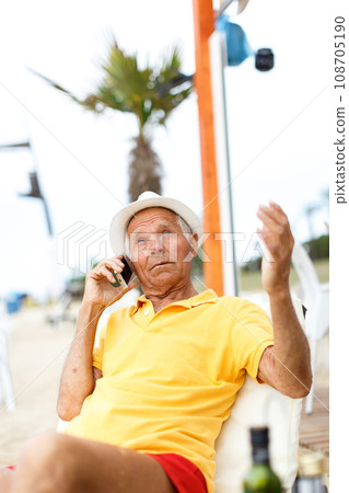 Satisfied cheery man resting and speaking phone Satisfied cheery man resting and speaking phone 108705190