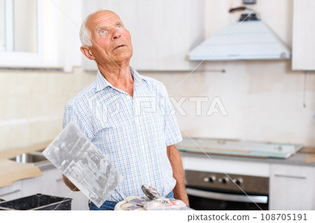 Man with plastering tools looking at repairable room Man with plastering tools looking at repairable room 108705191