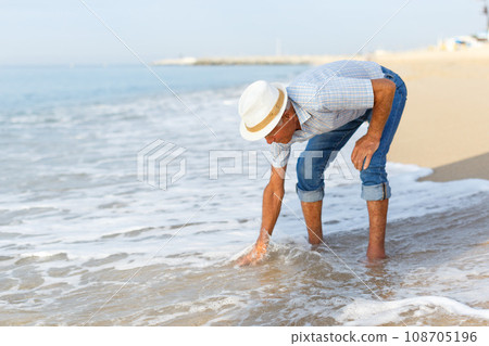 Elderly glad man checks the water temperature 108705196