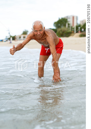 Jolly mature man checks the water temperature 108705198