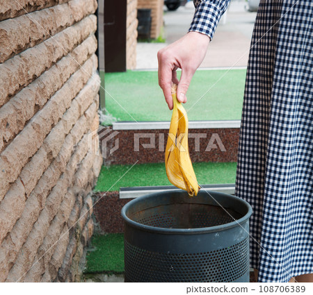 A girl throws a banana peel into the trash 108706389