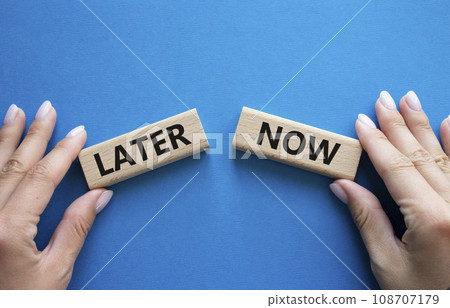 Now vs Later symbol. Concept word Now vs Later on wooden blocks. Businessman hand. Beautiful blue background. Business and Now vs Later concept. Copy space Now vs Later symbol. Concept word Now vs Later on wooden blocks. Businessman hand. Beautiful blue background. Business and Now vs Later concept. Copy space 108707179