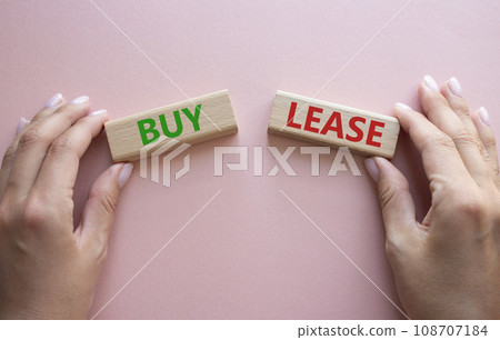 Buy or Lease symbol. Concept word Buy or Lease on wooden blocks. Businessman hand. Beautiful pink background. Business and Buy or Lease concept. Copy space 108707184