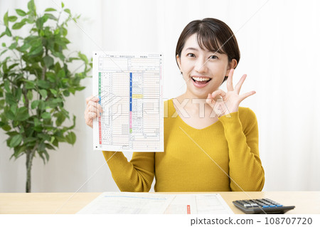 A smiling woman holding tax return documents A smiling woman holding tax return documents 108707720