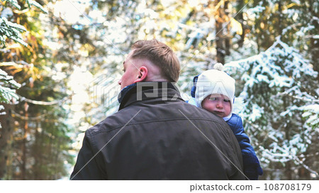 A father and his young son are walking through a winter forest. 108708179