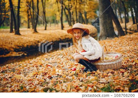 Cute child in a autumn park. Elegant little lady with blonde hair 108708200
