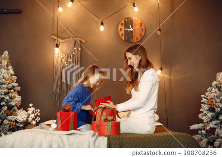 People reparing for Christmas. Mother playing with her daughter. Family is resting in a festive room. Child in a blue sweater. 108708236