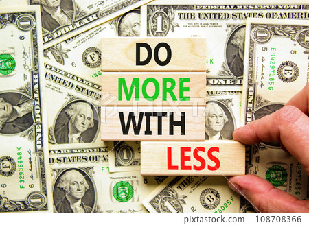 Do more with less symbol. Concept word Do more with less on beautiful block. Dollar bills. Beautiful background from dollar bills. Businessman hand. Business do more with less concept. Copy space. 108708366