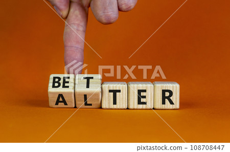Alter or better symbol. Businessman turns wooden cubes and changes the word 'alter' to 'better'. Beautiful orange background, copy space. Business and alter or better concept. Alter or better symbol. Businessman turns wooden cubes and changes the word 'alter' to 'better'. Beautiful orange background, copy space. Business and alter or better concept. 108708447