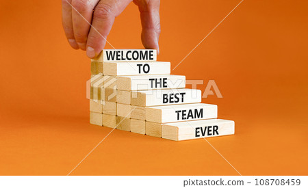 Welcome to best team symbol. Concept words Welcome to the best team ever on wooden block. Beautiful orange table background. Businessman hand. Business motivational and welcome to best team concept 108708459