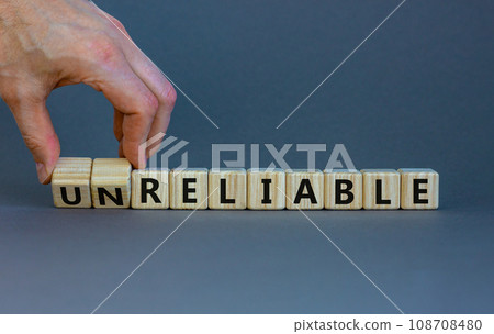 Unreliable or reliable symbol. Businessman turns wooden cubes and changes the word unreliable to reliable. Beautiful grey background, copy space. Business and unreliable or reliable concept. Unreliable or reliable symbol. Businessman turns wooden cubes and changes the word unreliable to reliable. Beautiful grey background, copy space. Business and unreliable or reliable concept. 108708480