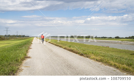 lonely cyclist is riding a gravel touring bike - biking on a levee trail along Chain of Rocks Canal near Granite City in Illinois lonely cyclist is riding a gravel touring bike - biking on a levee trail along Chain of Rocks Canal near Granite City in Illinois 108709550