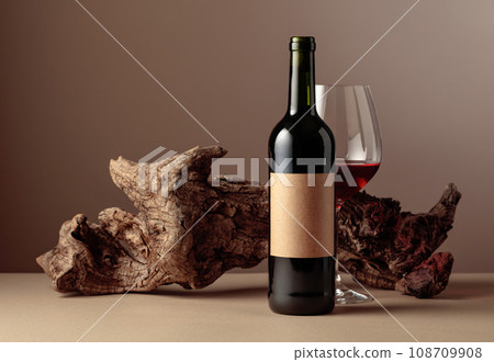 Bottle and glass of red wine with old weathered snag. 108709908