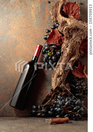 Bottle of red wine with blue grapes on a rusty background. 108709913