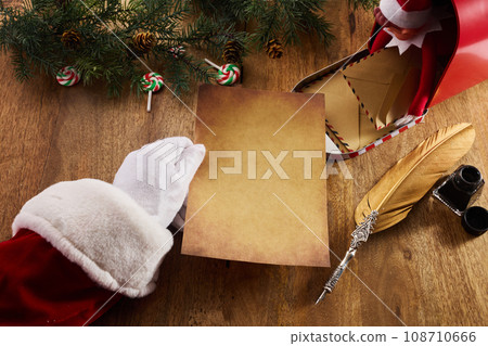 Santa Claus holding an empty wish list in his hands on wooden table 108710666