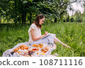 Beautiful woman on picnic. She smiles, eats strawberries and enjoys summer. 108711116