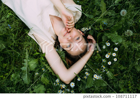 Beautiful woman with natural beauty without makeup lies in the grass in summer Beautiful woman with natural beauty without makeup lies in the grass in summer 108711117