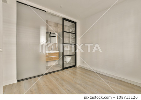 an empty room with wood flooring and white paint on the walls, there is a mirror in the door 108713126