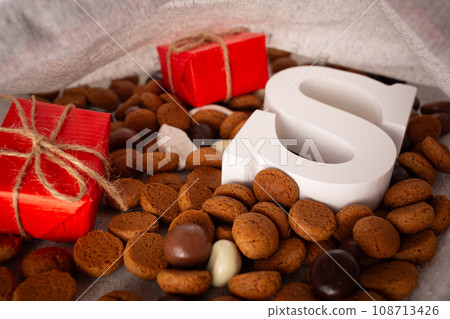 St.Nicholas day 5th of December, chocolate spicy ginger cookies and letters in white burlap sack close up St.Nicholas day 5th of December, chocolate spicy ginger cookies and letters in white burlap sack close up 108713426