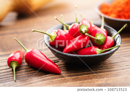 Bowl of red chili pepper pods and red hot pepper ground to powder on background. Bowl of red chili pepper pods and red hot pepper ground to powder on background. 108713523