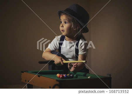 Charming child in retro clothes playing toy billiards 108713552