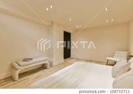 a bedroom with white walls and wood flooring in the middle, there is a bed on the right side a bedroom with white walls and wood flooring in the middle, there is a bed on the right side 108715711
