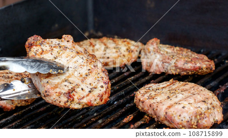 Grilled meat steak on stainless BBQ grill with flames on dark background. Food and cuisine concept. 108715899