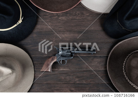 Gun with old west hats on table. Top view. Gun with old west hats on table. Top view. 108716166