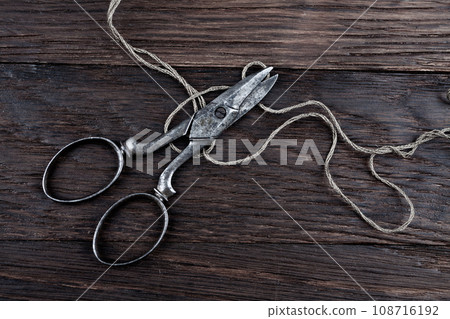 Antique old vintage retro scissors with thread on wooden table. Antique old vintage retro scissors with thread on wooden table. 108716192